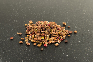 Whole dried sumac berries on a black cutting board