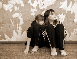 Two frightened children against   background of   gray ruined wall