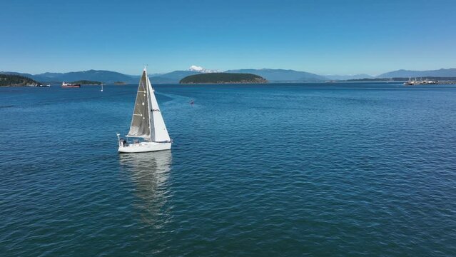 Drone shot of a sailboat as it travels through the San Juan Islands.