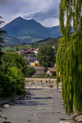 The upright landscape of Bressanone Brixen. The iconic town view with the river, houses, waterfall, mountains and sky.