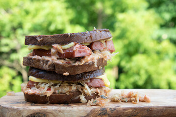 Reuben sandwich with smoked gouda cheese oozing over sides. Non-traditional Reuben sandwich made with kielbasa sausage.