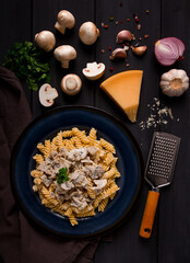 Fusilli pasta, with champignons in cream sauce, top view, with ingredients, on a wooden table, no people,