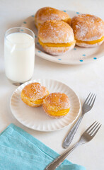 Bola de Berlim, or Berlin Ball, a Portuguese pastry made from a fried doughnut filled with sweet eggy cream with cup of milk on the table