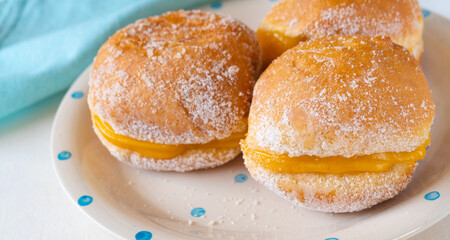 Bola de Berlim, or Berlin Ball, a Portuguese pastry made from a fried doughnut filled with sweet eggy cream on the table
