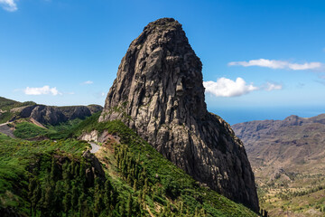 Scenic mountain road with view on massive volcanic rock formation Roque de Agando in Garajonay National Park on La Gomera, Canary Islands, Spain, Europe. Lava cone of old volcano. Sunny day in summer