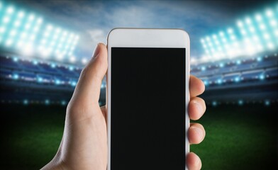 Hand hold smartphone with a blank screen on the stadium background