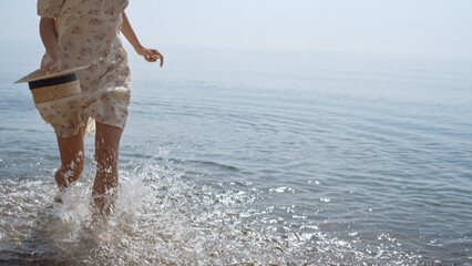 Unknown carefree lady running on sea waves in slow motion. Slim woman legs