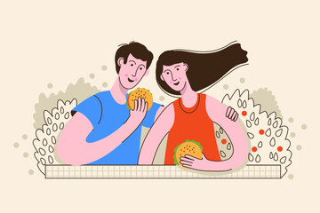 Happy young couple spending time together, resting in nature, eating burgers. Summer vacation