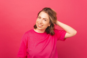Fototapeta premium A portrit picture of a beautiful young woman smiling near a pink wall