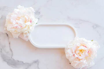 Top view of empty concrete tray with peony flowers on marble table. Mockup presentation for goods or cosmetics.