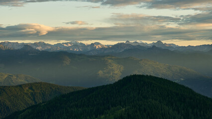 Fototapeta premium dreamy landscape with the moutians of the central alps in the distance and hazy sunset in the austrian alps near Dachstein