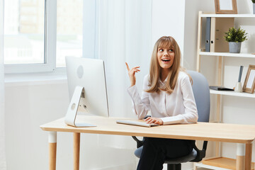 Excited happy adorable blonde businesswoman worker freelancer point finger look up have good work idea in light modern office work on computer online pondering or making decision. Copy space