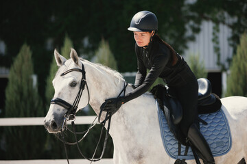 Equestrian sport. Portrait of young woman, female rider training at riding arena in summer day,...