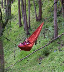 Vertical shot of woman yawning in a hammock in the woods 