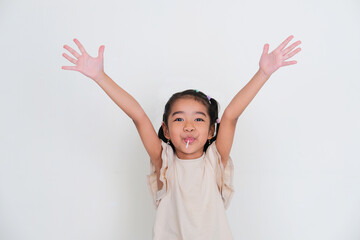 Asian little girl raising both hand up while eating lollipop to show happiness