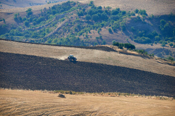 farm tractor at work on the slopes with dust in the middle of hot summer