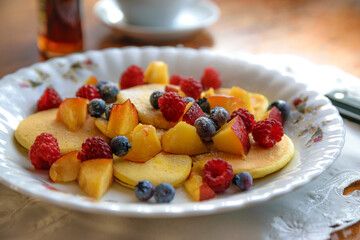 Idea for a tasty and healthy breakfast - pancakes with different fruits with maple syrup and sprinkled with powdered