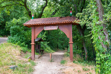 Traditional hungarian wooden entrance gate. On the sign is written in Hungarian "Sipos Hegyi Parkerdő", which means "Sipos Mountain Park Forest".