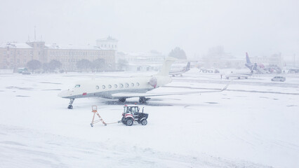 Snow covered commercial plane at the airport. Close-up of the plane after snowfall. Winter bad weather conditions.
