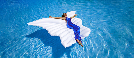 Elegant fashion model in long gown dress is lying on a mattress in the pool . Elegance. Classy...