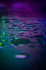 Beautiful macro photo of water drop reflection, lying on surface, front view. Close up of liquid with side lighting from displays.