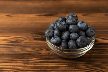 Blueberries in a bowl on a brown textured background. Ripe and fresh blueberries. Vitamins. Healthy food. Juicy berry. Copy space. Place for text