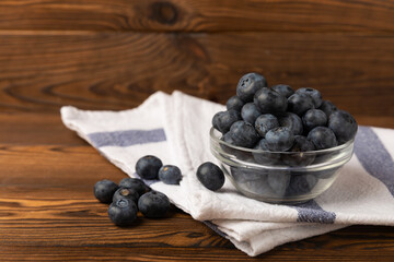 Blueberries in a bowl on a brown textured background. Ripe and fresh blueberries. Vitamins. Healthy food. Juicy berry. Copy space. Place for text