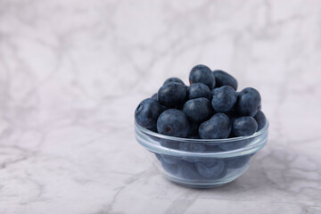 Blueberries in a bowl on a white marble background. Ripe and fresh blueberries. Vitamins. Healthy food. Juicy berry. Copy space. Place for text