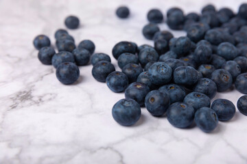 Blueberries on a white marble background. Ripe and fresh blueberries. Vitamins. Healthy food. Juicy berry. Copy space. Place for text