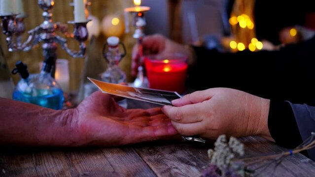 magic session with old photographs of deceased relatives, Female Fortuneteller or esoteric Oracle, longing for ancestors, communication with world spirits, candles burning, attributes of occultism