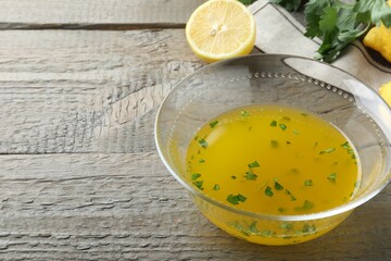 Bowl with lemon sauce and ingredients on wooden table, space for text. Delicious salad dressing