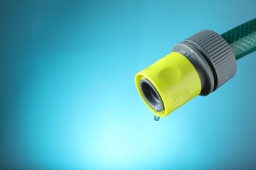 Water dripping from hose on light blue background, closeup. Space for text
