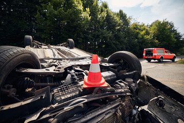 Damaged car on the roof after accident against fire rescue vehicle. Selective focus on traffic...
