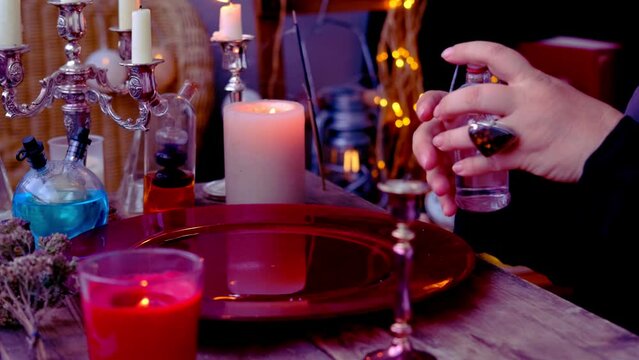 red dish with water, candle lights in dark room of fortuneteller, esoteric Oracle, psychic throws dripping liquid, session of magic, divination for future, prophecies from the world of spirits