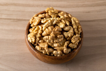 Bowl full of peeled walnuts on a wooden background
