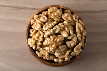 Bowl full of peeled walnuts on a wooden background