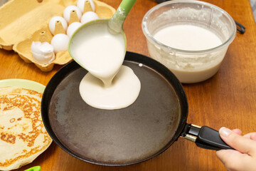 The dough is poured ladle into a hot oiled frying pan. The process of baking pancakes. Traditional treat for Maslenitsa holiday.