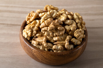 Bowl full of peeled walnuts on a wooden background