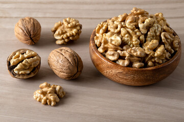 Peeled walnuts and whole walnuts on wooden background