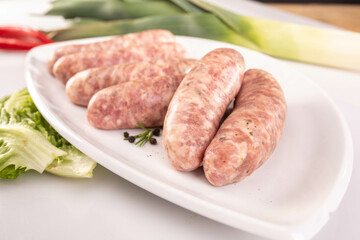 Raw white sausage on a white plate. Composition with traditional Polish white sausage, easter delicacy.