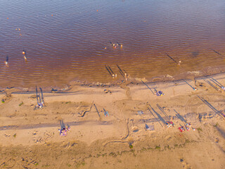 People sunbathe and swim in the lake. Bird's-eye view.