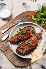 Imam bayildi. Traditional delicious Turkish food: halves of baked eggplant stuffed with vegetables on a plate. Selective focus
