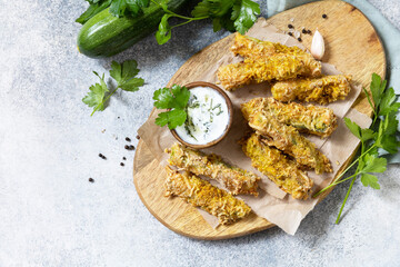 Healthy tasty snack, summer food. Zucchini fries. Crispy Zucchini sticks in breadcrumbs, with cheese with garlic yogurt sause. View from above. Copy space.