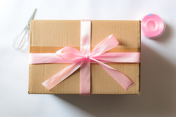 Cardboard box with a pink ribbon. Gift