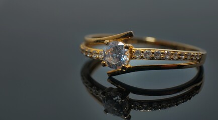 Gold jewelry ring with diamond on reflected black table