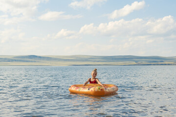 girl bathes in the lake on a mattress