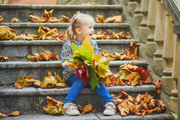 Adorable preschooler girl enjoying nice and sunny autumn day outdoors