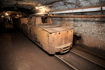 Dirty electric locomotive in the mine underground. Technologies of underground mining. Industrial equipment in the mine.