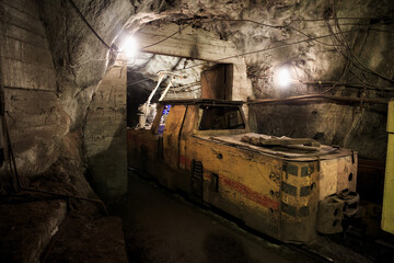 Dirty electric locomotive in the mine underground. Technologies of underground mining. Industrial equipment in the mine.