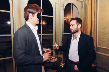 Company of friends in masquerade masks in restaurant